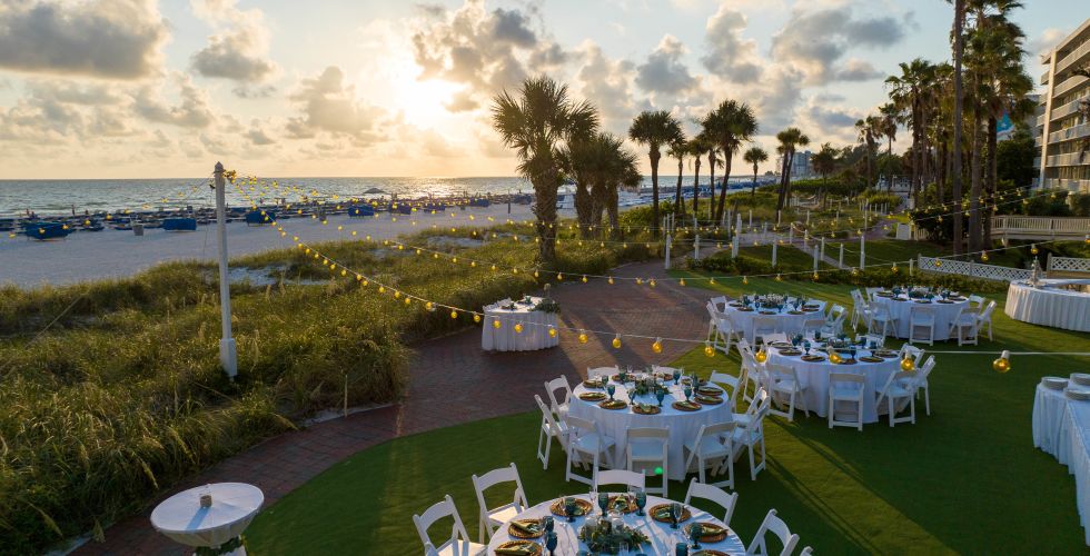 A Group Of Tables And Chairs On A Lawn By A Body Of Water