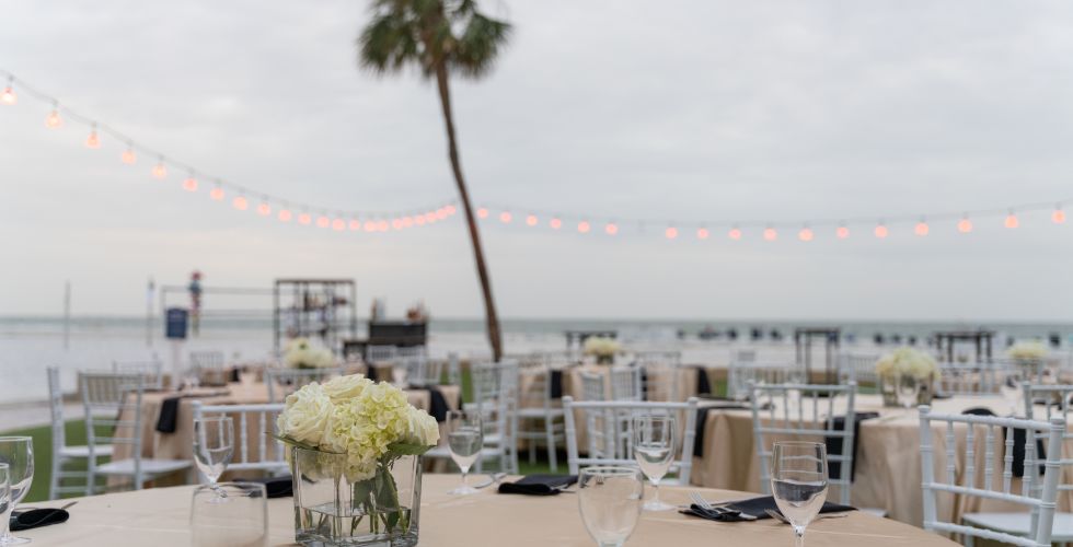 A Table With Glasses And Plates On It By A Body Of Water
