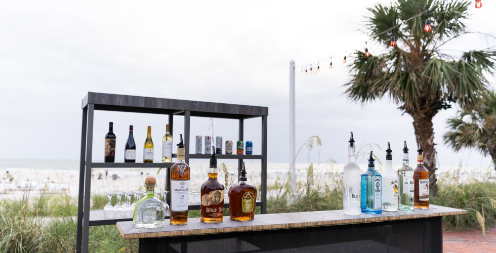 A Table With Bottles Of Alcohol On It By A Beach