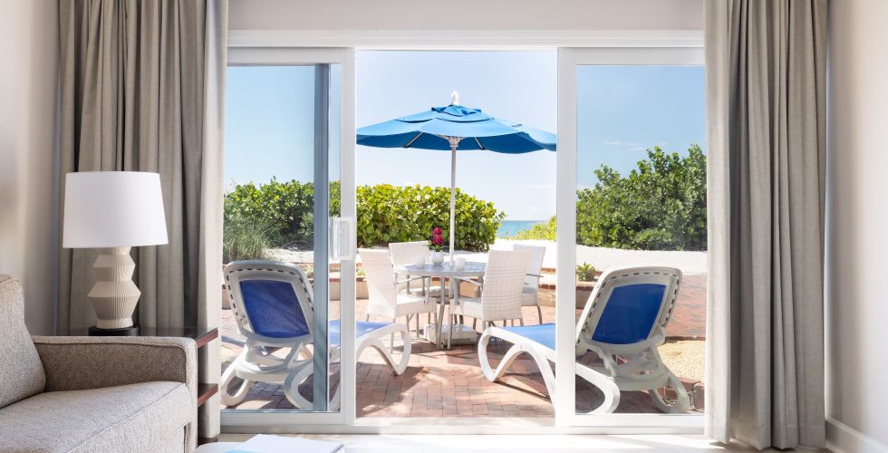 A Room With A Table Chairs And A Window With A View Of The Ocean