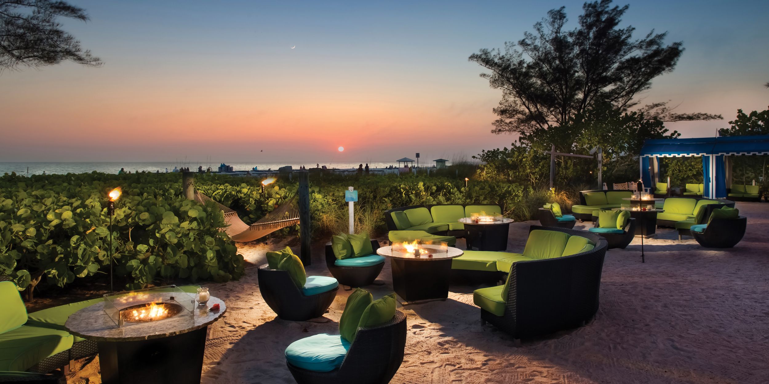 Multiple chairs & tables outside TradeWinds Island Resorts with a sunset view